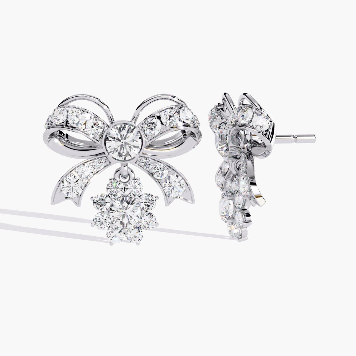 A pair of white gold bow earrings with dangling clear round diamonds. The bows are made of small clear stones with white gold accents.