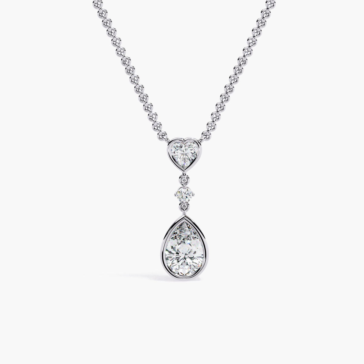 A white gold chain necklace with a pear-shaped diamond pendant and a heart-shaped diamond accent.