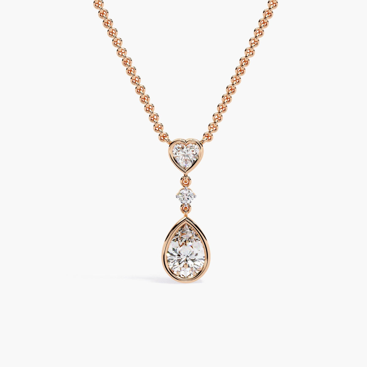 A rose gold chain necklace with a pear-shaped diamond pendant and a heart-shaped diamond accent.