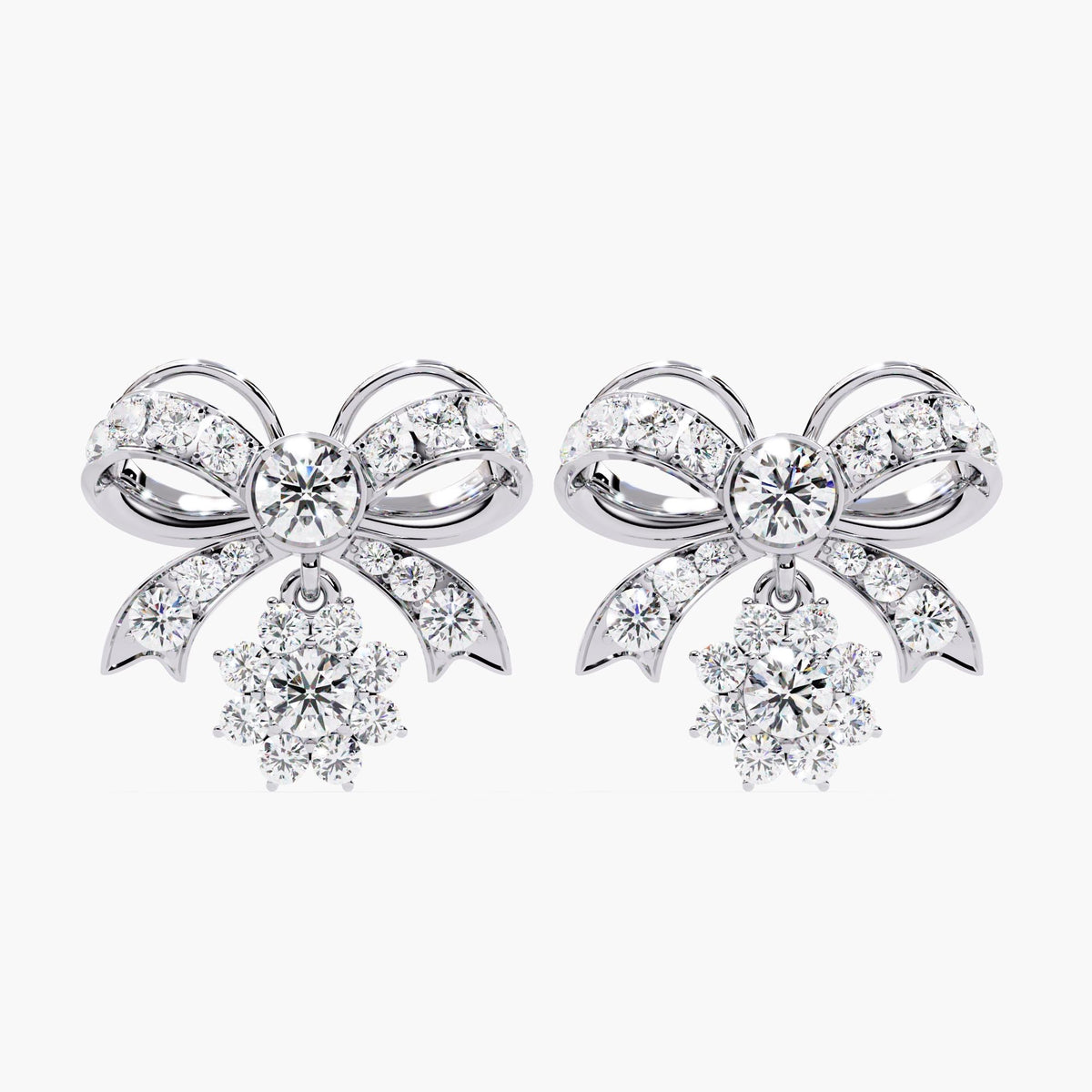 A pair of white gold bow earrings with dangling clear round diamonds. The bows are made of small clear stones with white gold accents.
