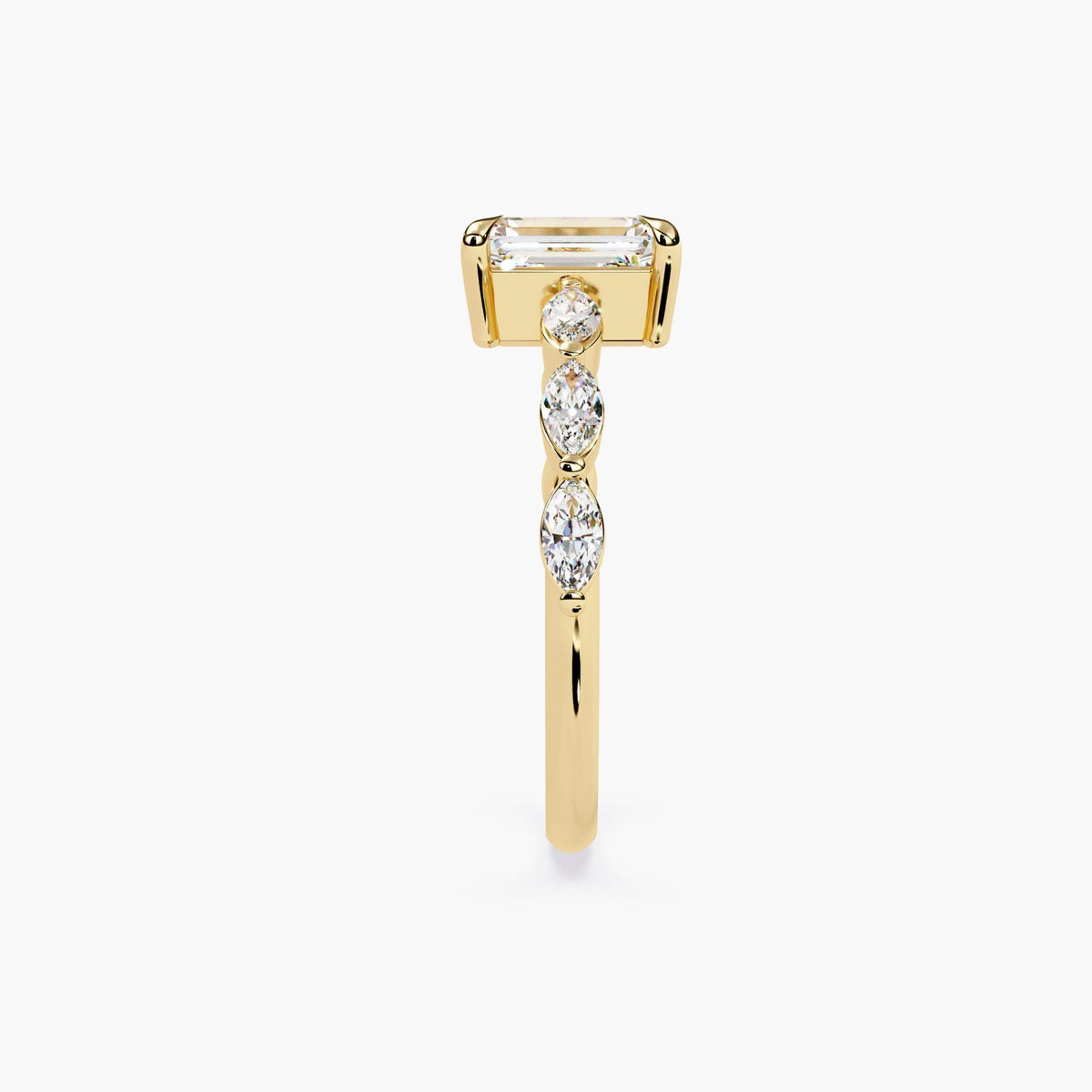 A yellow gold emerald-cut moissanite engagement ring. The ring features a large, radiant emerald-cut moissanite center stone.