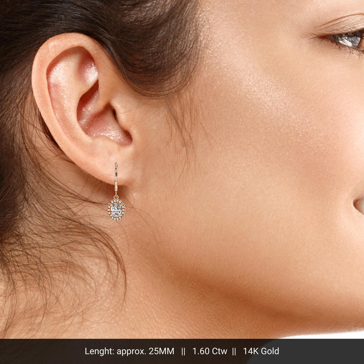 A 14K rose gold oval halo diamond drop earring worn on a model. The earring hangs just below the earlobe, showing its 25mm length and delicate leverback closure with 1.60 ctw of lab-grown diamonds.