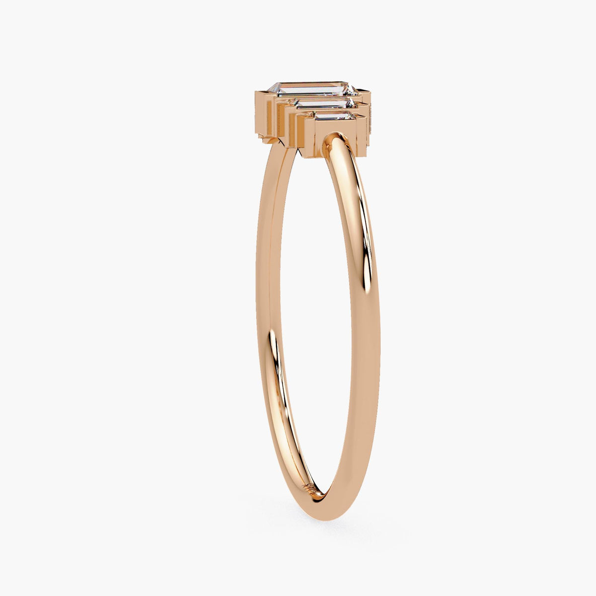 Side view of a 14k rose gold baguette diamond ring, showing the height of the stepped half bezel setting and slim 1.3 mm polished band.
