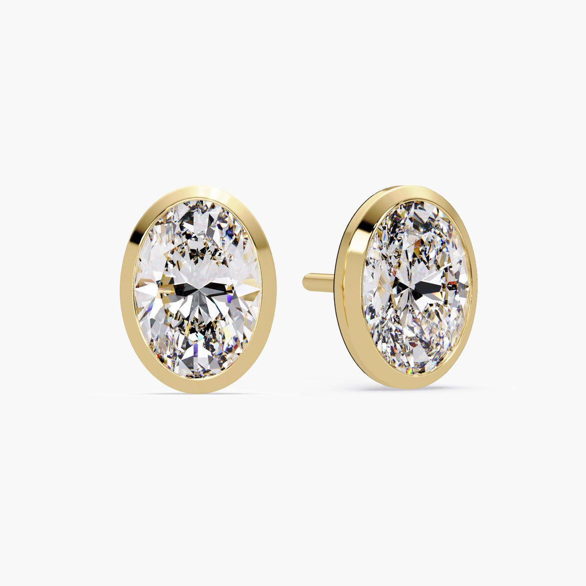 14k yellow gold oval diamond stud earrings featuring bezel set lab grown diamonds. The low-profile setting sits flush against the ear for a clean and modern look.