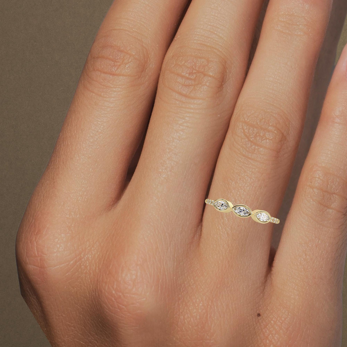 14K yellow gold ring featuring three marquise diamonds set in bezel settings, worn on a finger with small round diamonds on the sides of the band.
