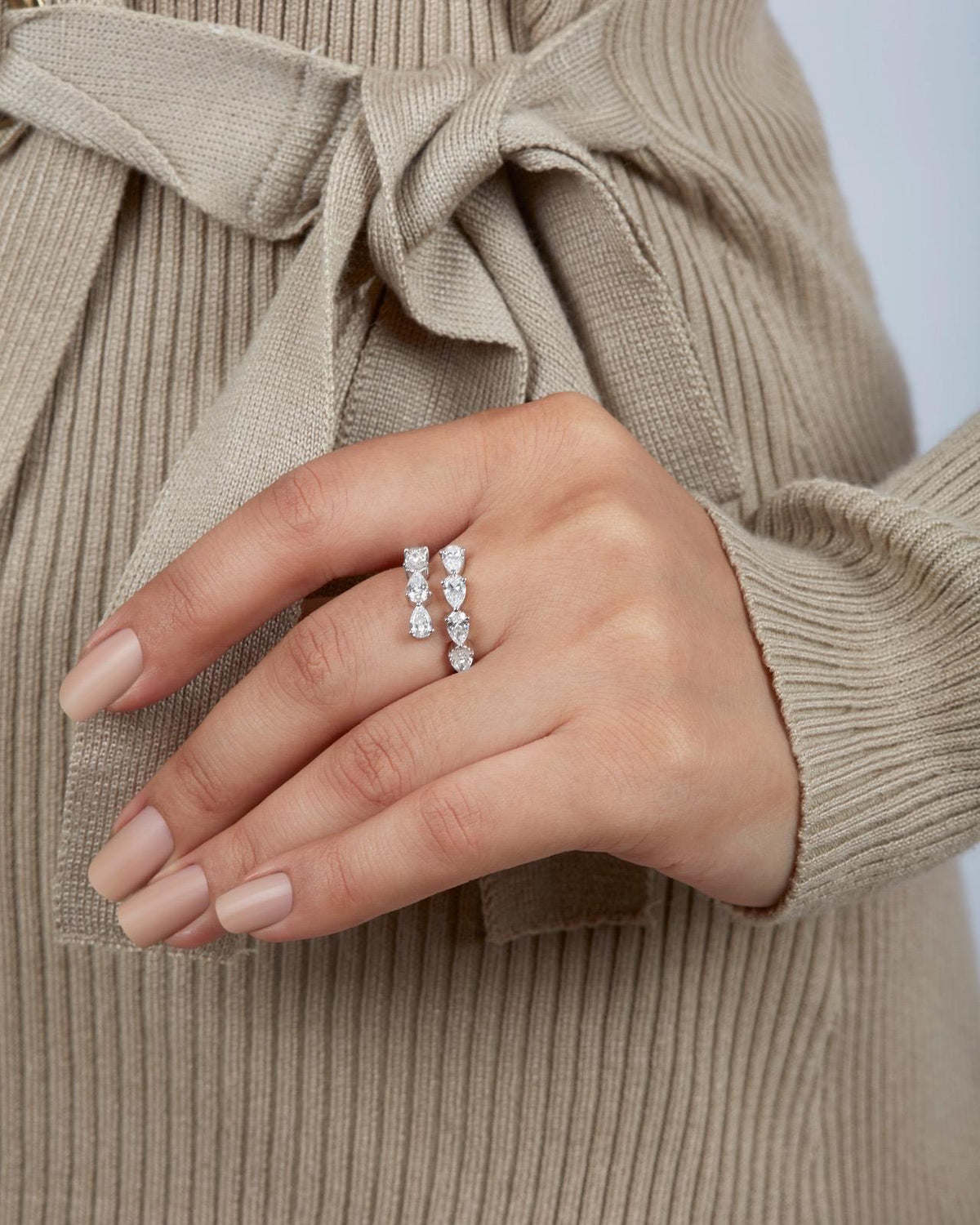 Top-down view of a woman's hand wearing a white gold bypass ring with pear cut lab grown diamonds. The ring’s open wrap design creates a mirrored double row effect across the finger.