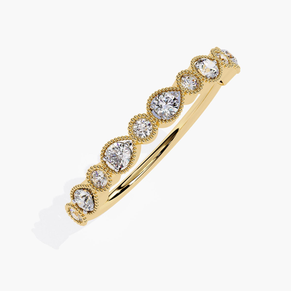 A close-up view of a yellow gold diamond band featuring alternating pear-shaped and round bezel settings, each holding a round brilliant diamond. The milgrain detailing along the bezels adds a vintage touch. This versatile band is ideal for stacking with other rings or wearing alone, and its Art Deco-inspired design makes it a perfect complement to engagement rings.