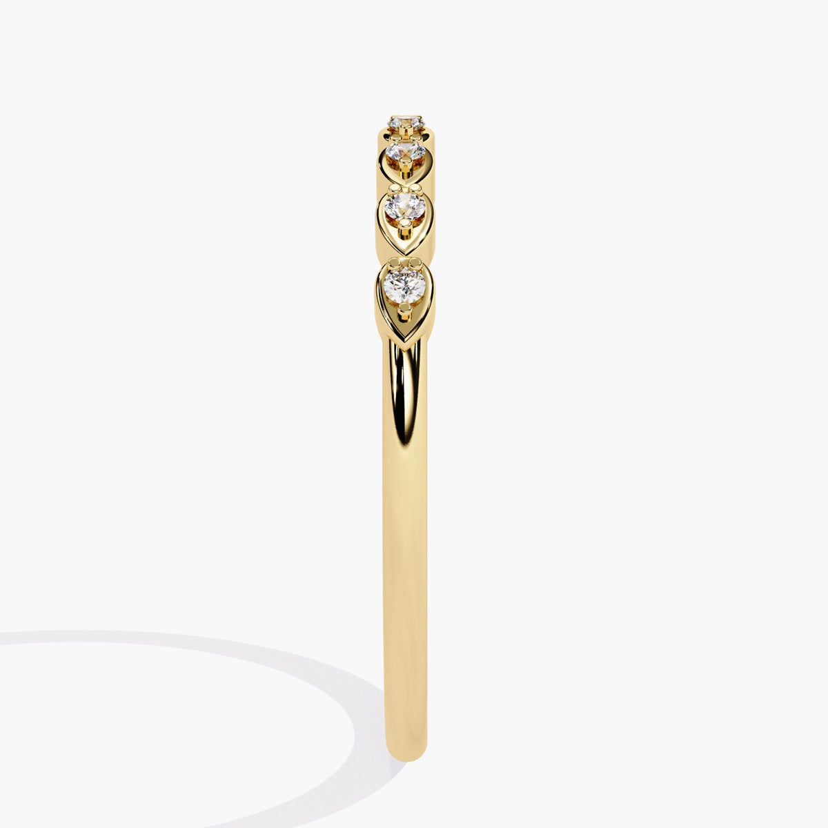 Side profile view of a 14k yellow gold diamond band showcasing seven round diamonds in alternating pear-shaped bezel settings. The slim, polished band highlights the low-profile, stackable design perfect for everyday wear.