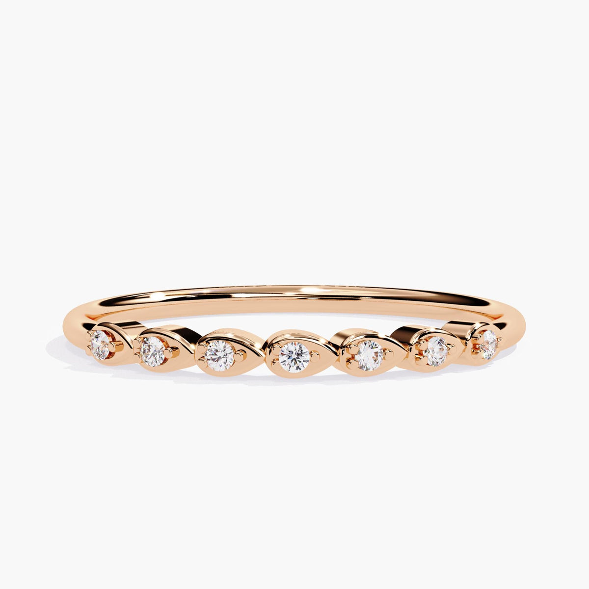 14k rose gold band featuring seven round diamonds set in alternating pear-shaped bezels, forming a delicate and low-profile stacking ring.