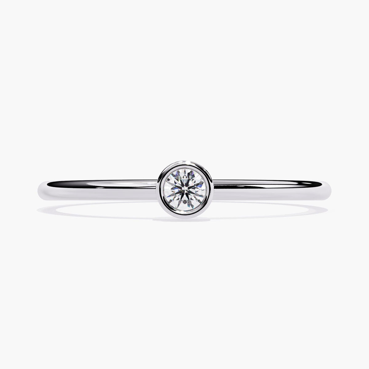a solitaire ring with a bezel set round natural diamond on a thin 14k white gold band, showcasing its minimalist and modern design.