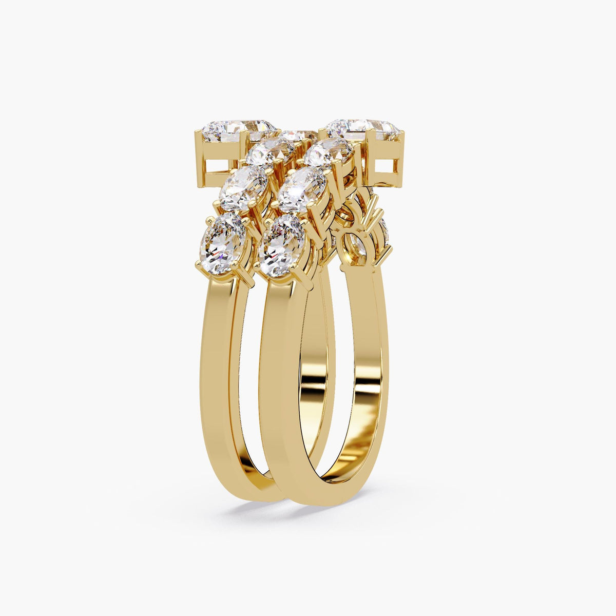 a spiral wrap ring in yellow gold featuring two emerald cut diamonds at each open end, with two rows of oval diamonds set in shared prongs along a curved bypass band.