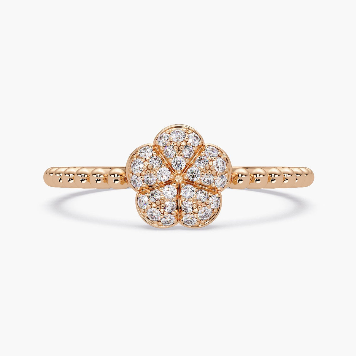 14k rose gold flower ring featuring a pavé diamond cluster in a five-petal floral shape. The petals are softly domed and outlined in warm-toned gold, creating a dimensional, puffy effect. The upper band has a beaded texture, adding contrast to the polished setting.