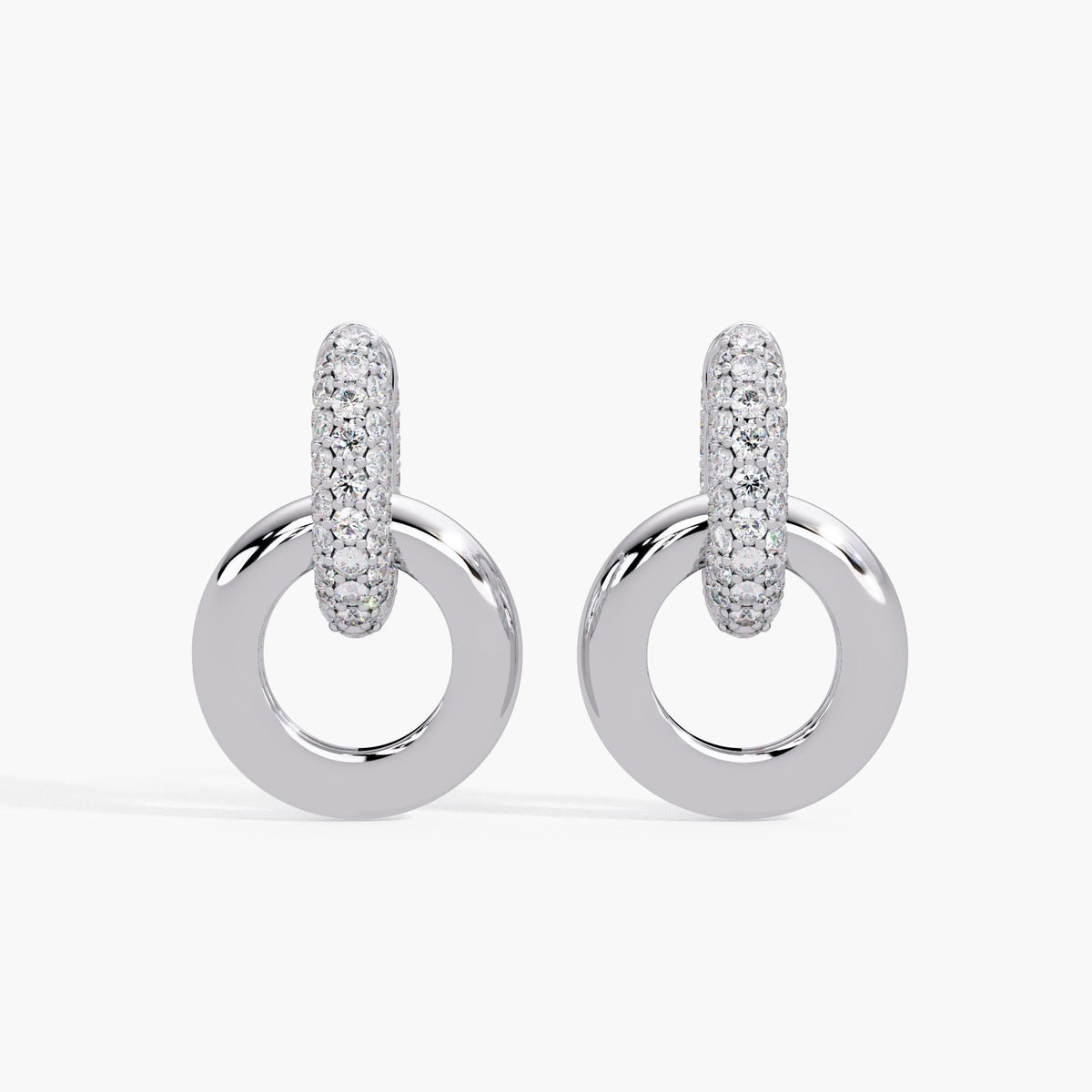 14K white gold interlocking circle earrings featuring a pavé-set diamond huggie hoop and a polished circular drop. The top hoop is covered in round brilliant lab-grown diamonds, while the bottom circle is thick, smooth, and highly reflective. These chunky white gold earrings have a convertible double hoop design, perfect for those searching for dangle hoop earrings, 14k gold statement hoops, or thick white gold drop earrings. A refined modern style ideal as a gift for her or anniversary jewelry.
