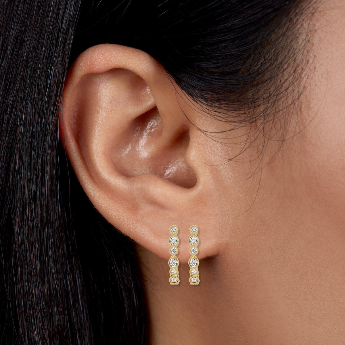 14K yellow gold diamond half hoop earrings. The earrings feature round brilliant lab-grown diamonds (EF color, VS+ clarity) in alternating teardrop and round bezels with milgrain detailing. Shown stacked on one lobe for an elevated, everyday look.