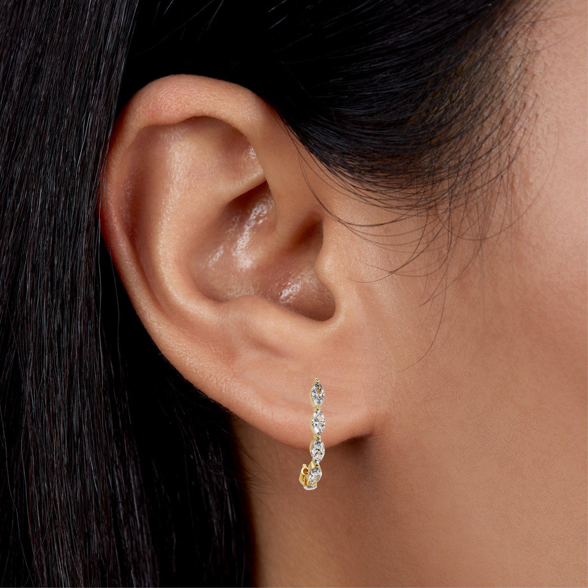 14K yellow gold marquise diamond hoop earrings worn on ear, 18MM half hoop single prong setting, lightweight minimalist design for everyday wear, bridal jewelry, or gift for her.