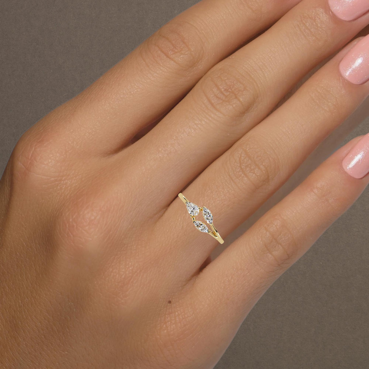 Three-stone diamond ring in 14K yellow gold featuring pear and marquise lab-grown diamonds in a floral-inspired open setting, photographed on hand for scale and styling