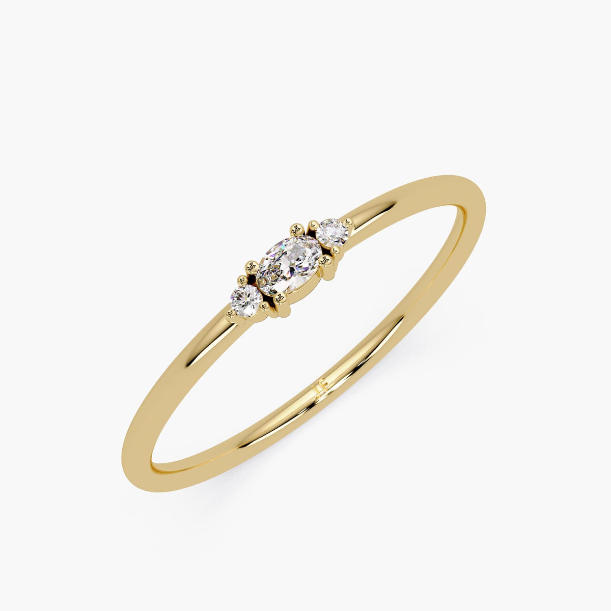 14K yellow gold ring featuring a slim 1.3mm band with a center oval-cut lab-grown diamond and two round side stones in a three-stone prong setting