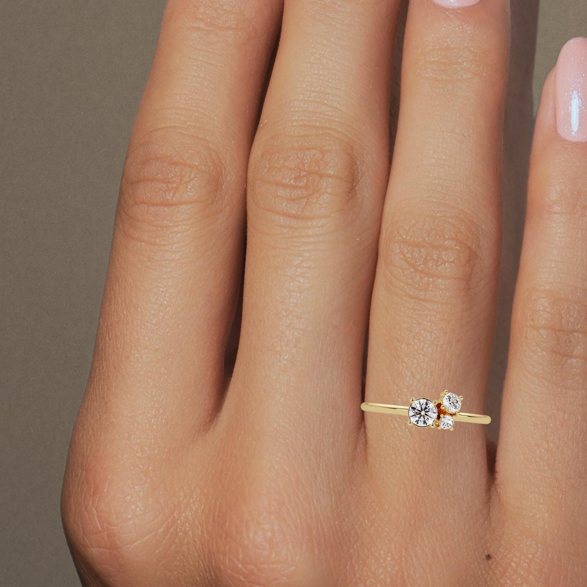 Model wearing a 14k gold three-stone lab diamond ring with a dainty graduated cluster design