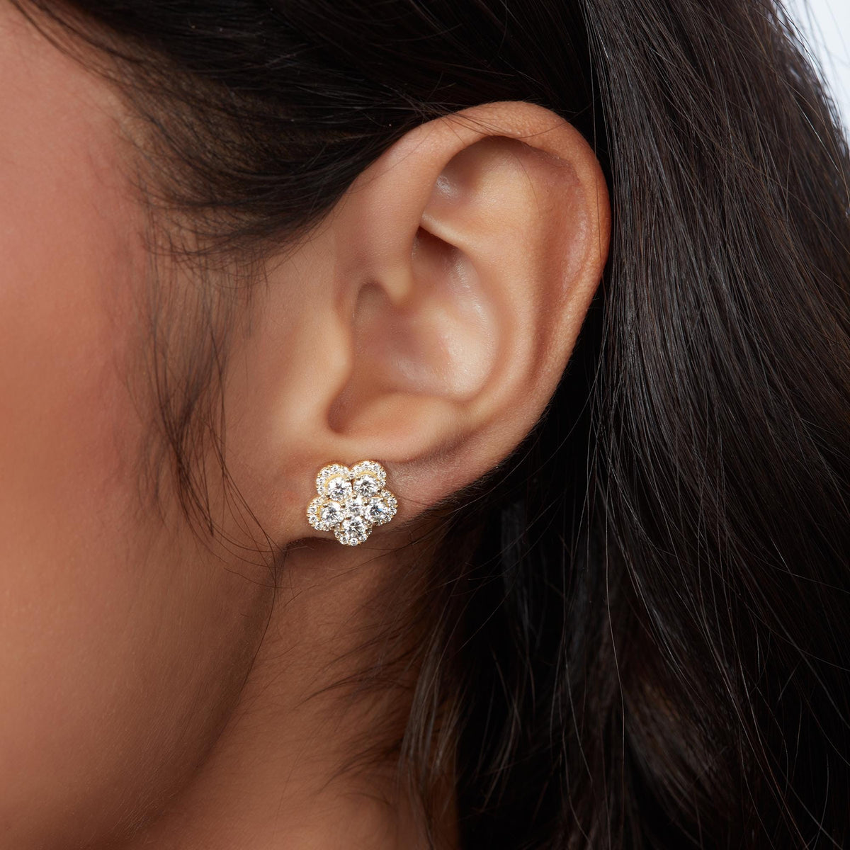14K gold floral lab-grown diamond stud earring with round brilliant diamonds in a flower cluster, worn on an ear.