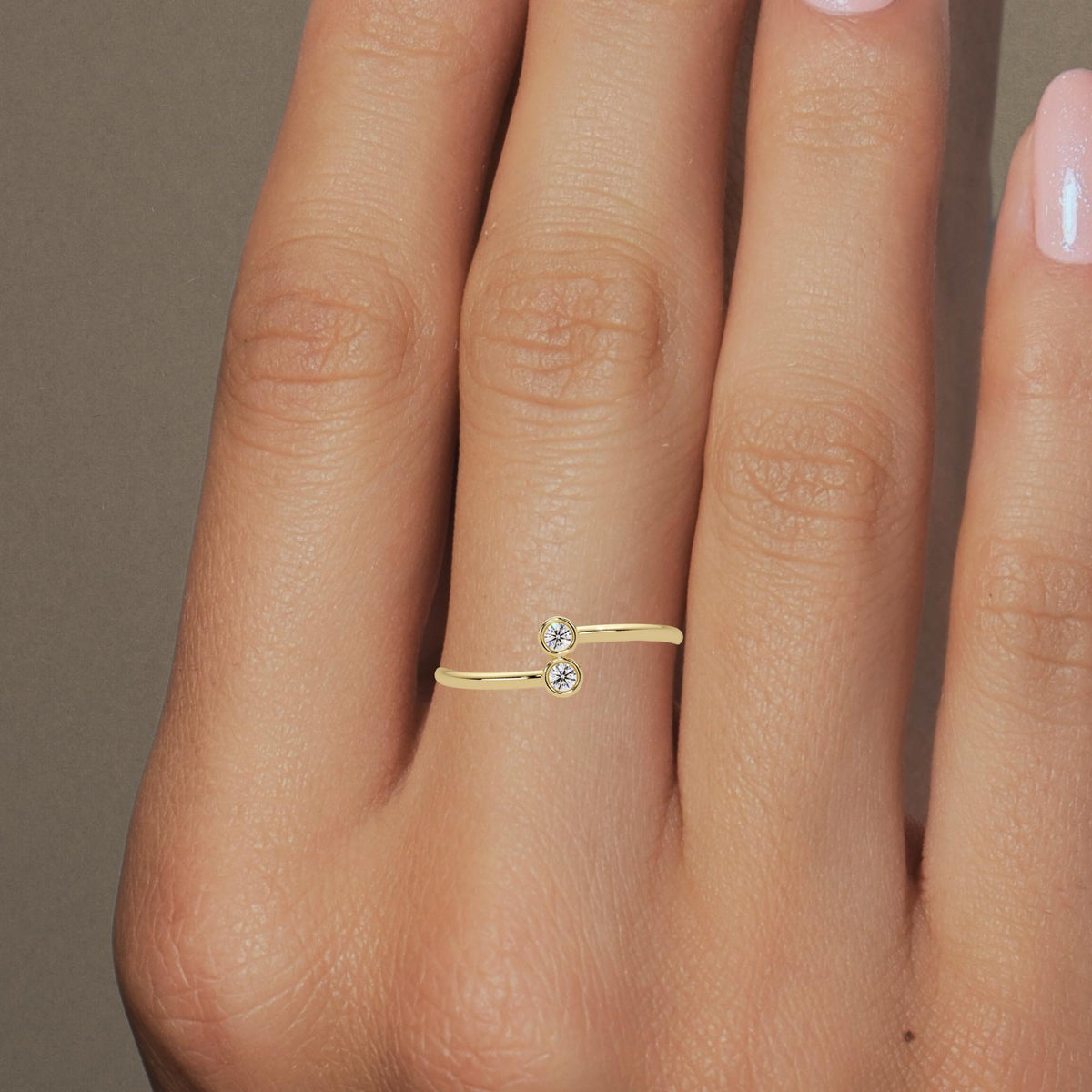 Dainty gold stacking band with sparkling bezel diamonds styled on hand.