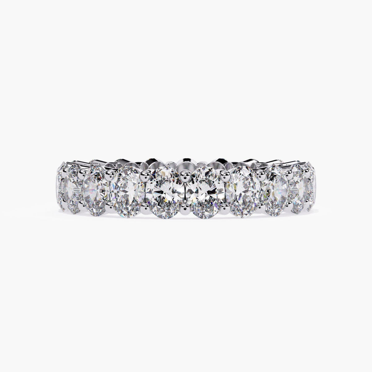 A white gold band ring with a row of oval shaped diamonds set in a pave setting.