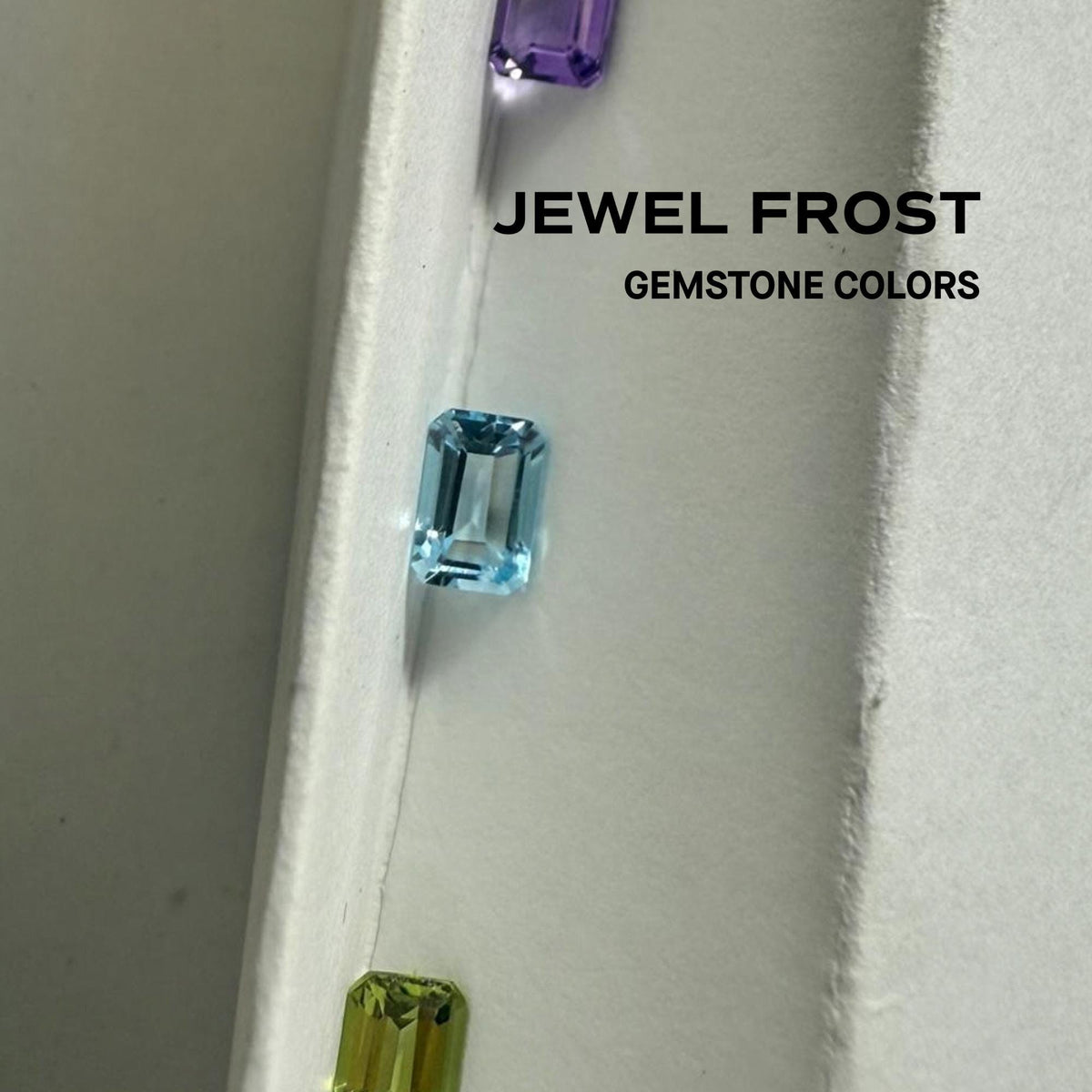 Loose natural sky blue topaz gemstone shown with other gemstone colors on white display.