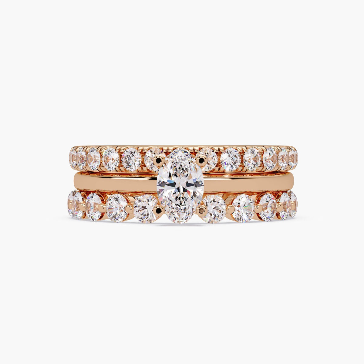 Oval lab grown diamond engagement ring set in 14K rose gold, featuring an oval solitaire center ring stacked with two round diamond bands for a bridal or stacking ring look.