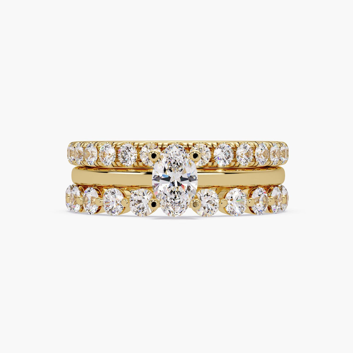 Oval lab grown diamond engagement ring set in 14K yellow gold, featuring an oval solitaire center ring stacked with two round diamond bands for a bridal or stacking ring look.