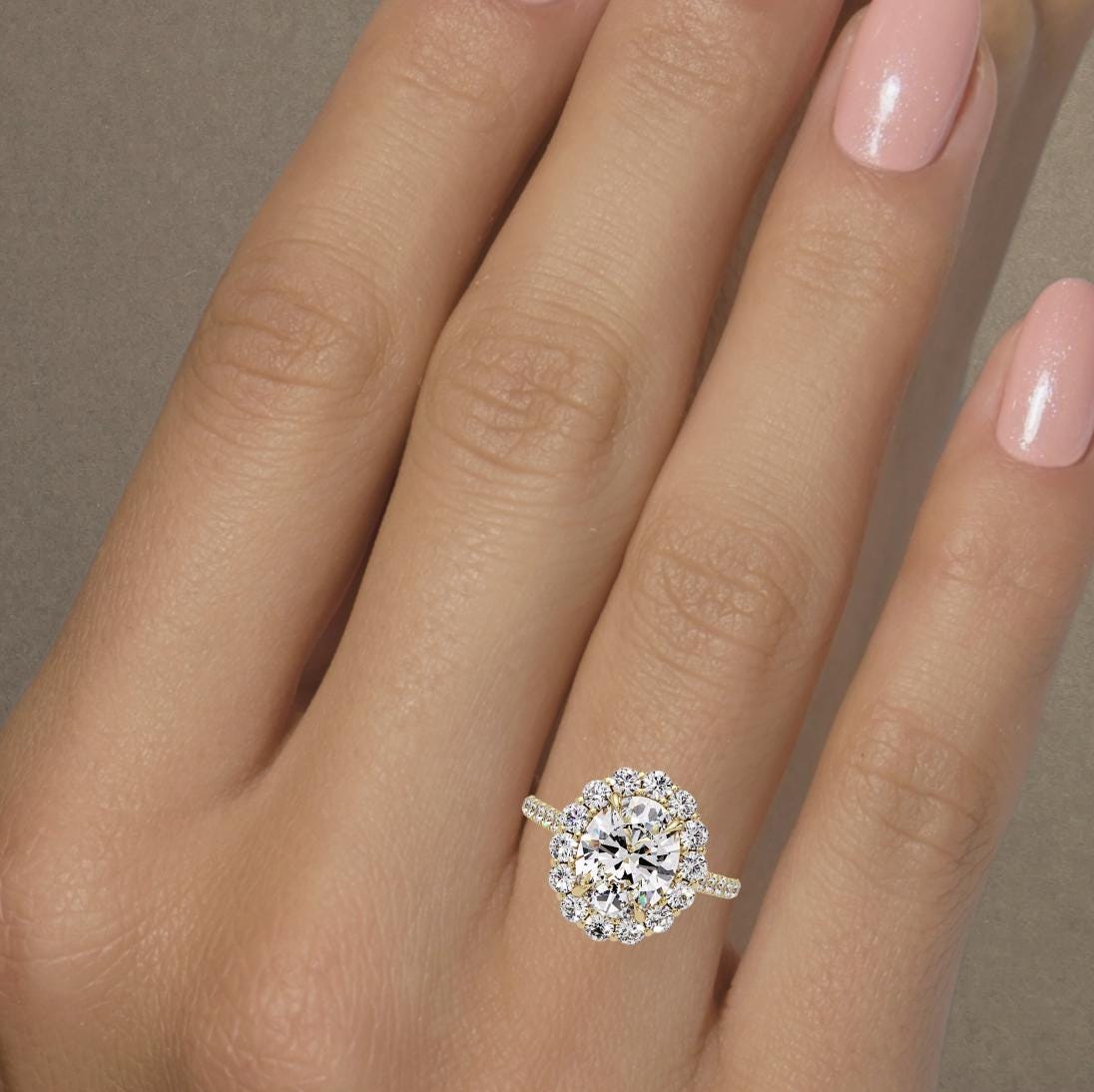 14K yellow gold oval halo engagement ring on hand featuring a 2.5 carat IGI certified oval lab grown diamond center with round diamond halo and pavé band, total 3.5 ctw cathedral setting