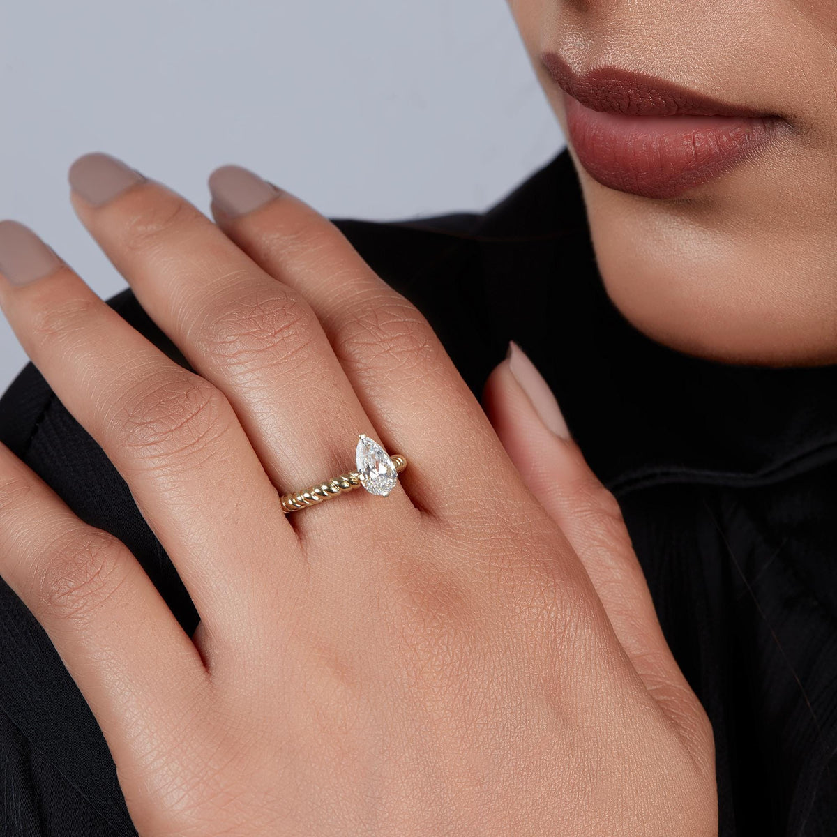 14K yellow gold ring featuring a pear-shaped diamond solitaire on a beaded band.