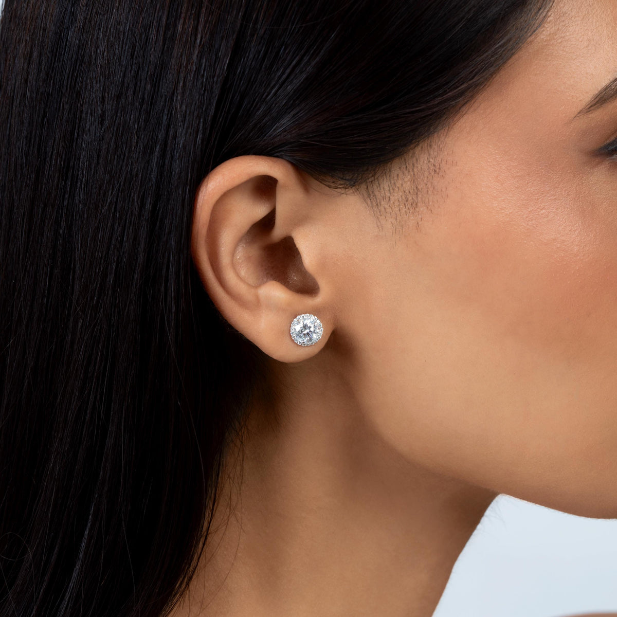 Close-up of a round lab-grown diamond cluster stud earring set in 14K gold, worn on an ear.