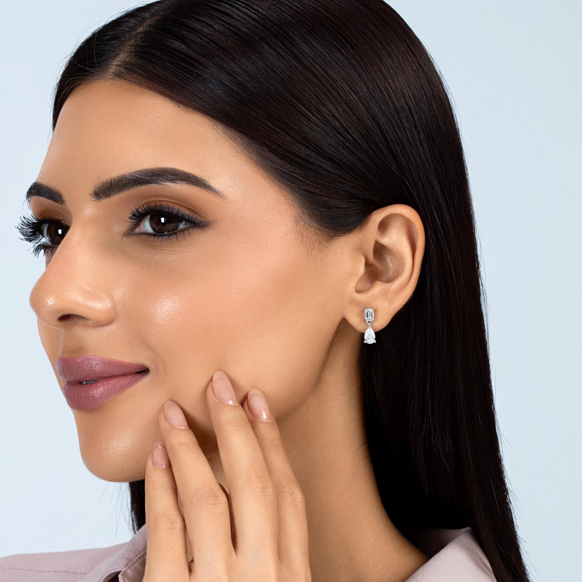 14K white gold lab-grown diamond drop earring with an emerald-cut stud and pear-shaped diamond dangle, worn on an ear.