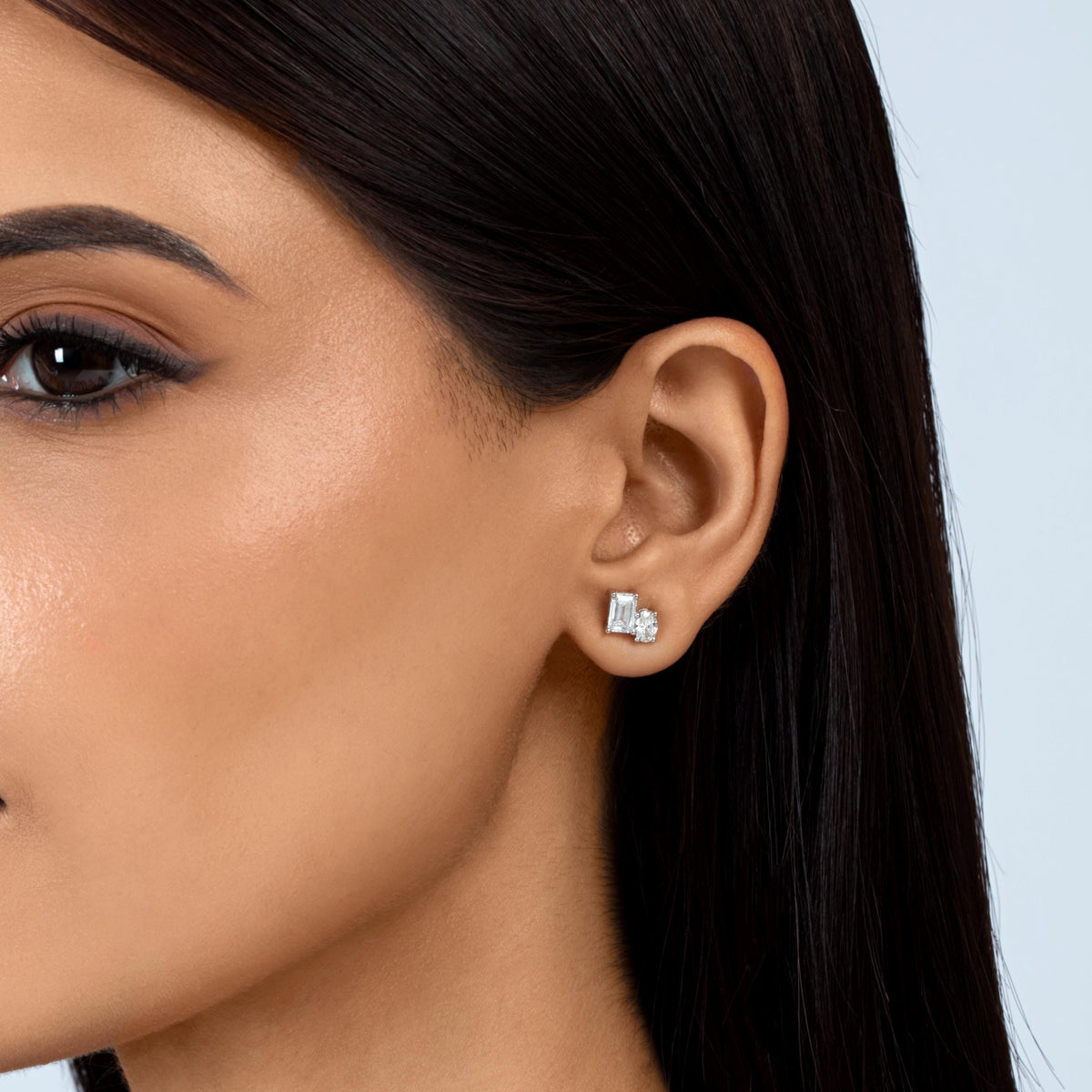 14K gold lab-grown diamond stud earring featuring emerald and oval-cut colorless diamonds in prong settings, worn on an ear.