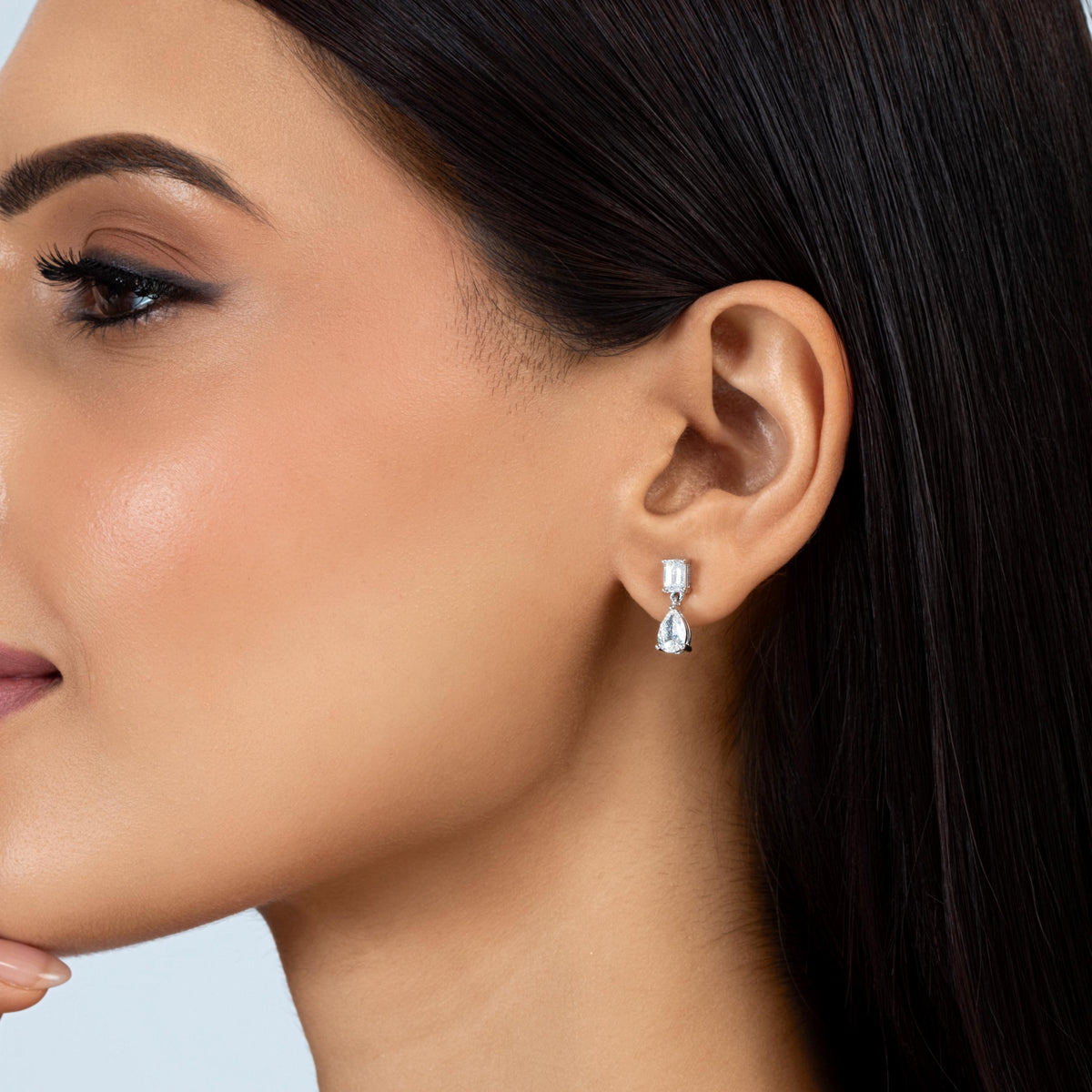 14K white gold lab-grown diamond drop earring with an emerald-cut stud and pear-shaped diamond dangle, worn on an ear.