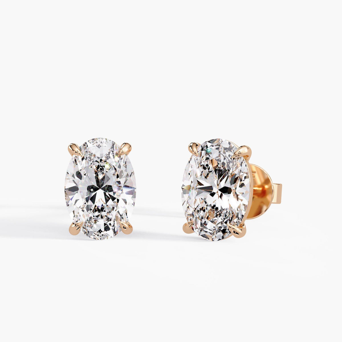 Oval-cut lab-grown diamond stud earrings in 14K rose gold with classic four-claw solitaire settings and pushback closures for bridal or everyday wear.