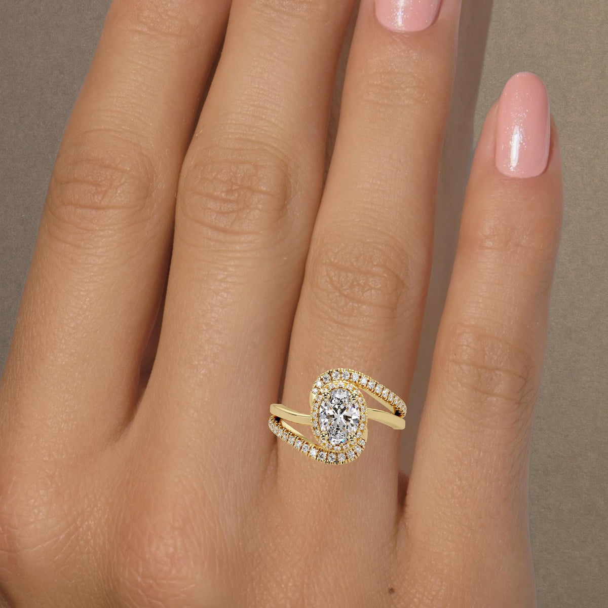 14K yellow gold oval diamond engagement ring worn on hand with a 1 CT lab-grown center and pavé bypass band