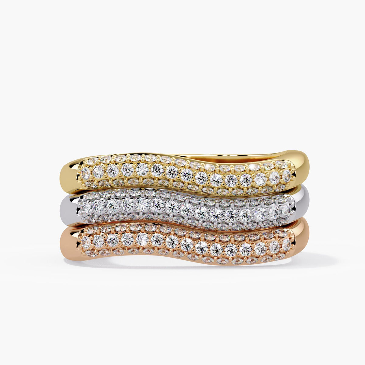 Three wavy natural diamond bands stacked in 14K yellow, white and rose gold, each with a curved pavé diamond front and smooth polished edges.