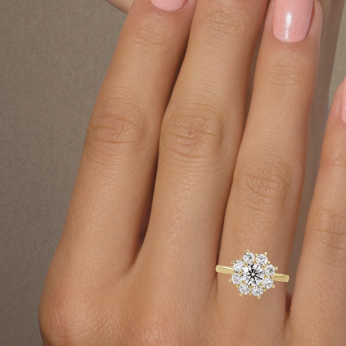 Daisy diamond engagement ring worn on the hand, with a round lab grown diamond center, eight diamond petals and a slender 14K yellow gold band.
