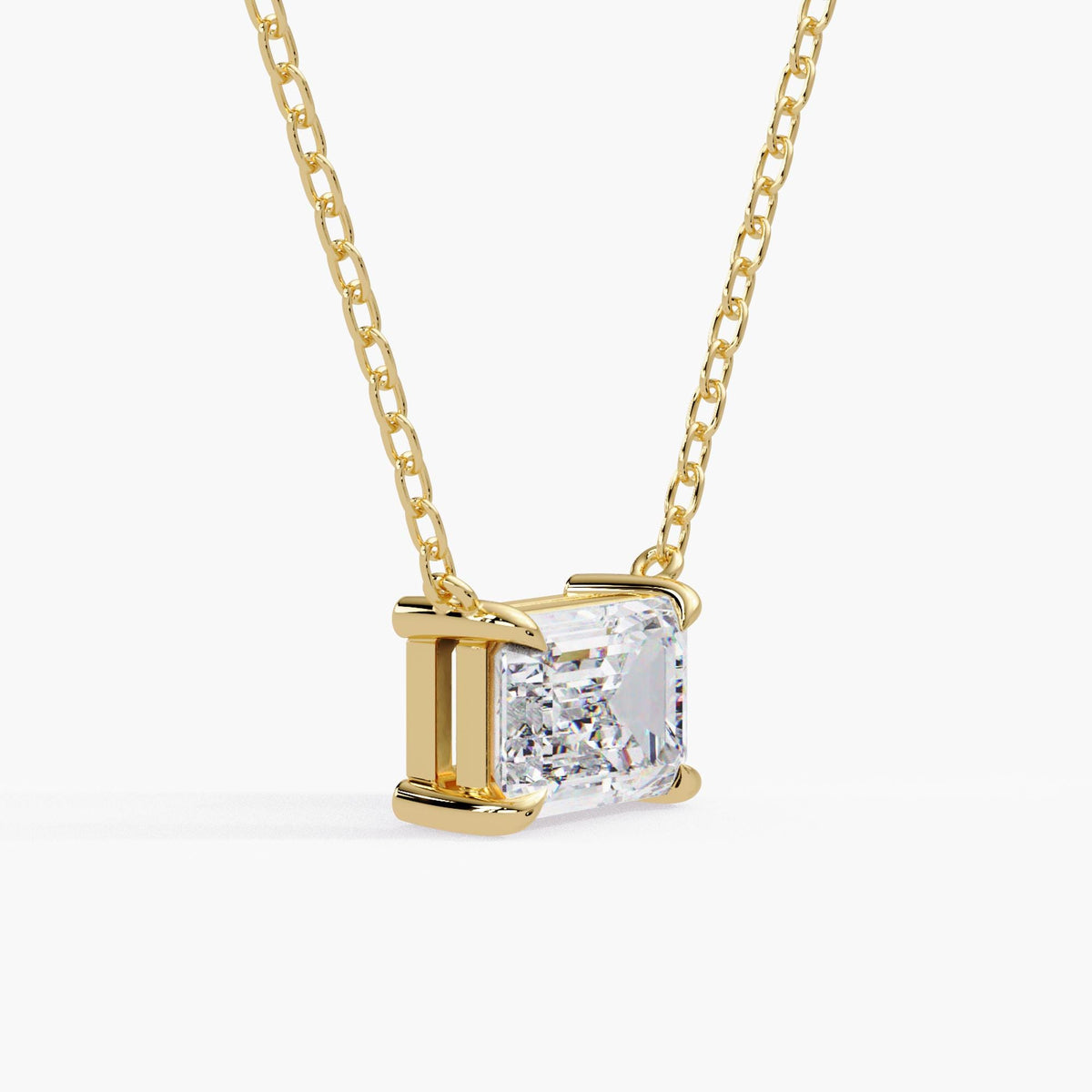 east-west diamond pendant in solid yellow gold, showing the emerald-cut facets, claw prongs and open basket setting.