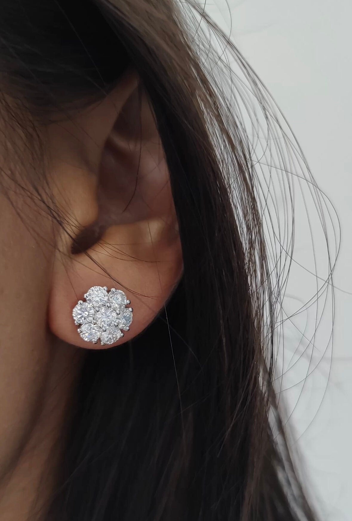 A 14k white gold floral cluster earring worn on the ear, featuring round lab-grown diamonds in a bold flower-like design that sits prominently on the lobe.