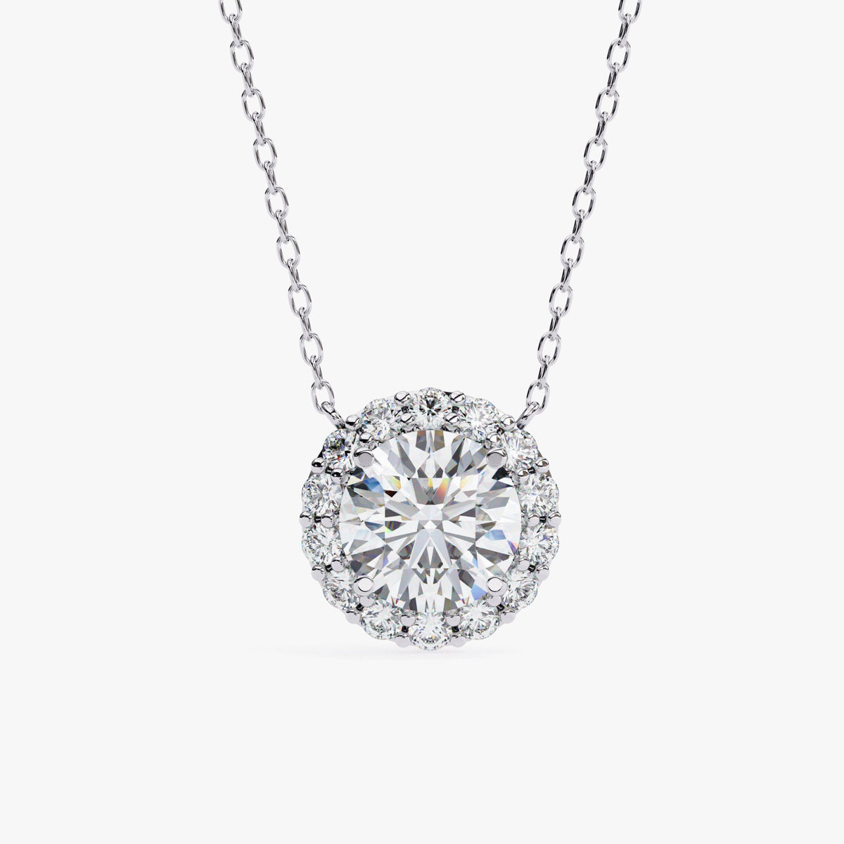 A white gold chain necklace with a round pendant featuring a single, clear, round-cut stone surrounded by a halo of smaller, clear stones.