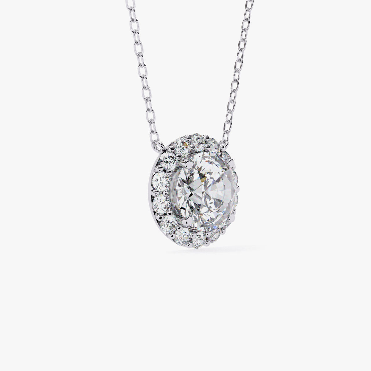 A white gold chain necklace with a round pendant featuring a single, clear, round-cut stone surrounded by a halo of smaller, clear stones.