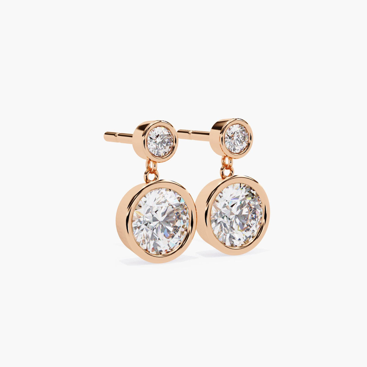 Angled view of 14k rose gold dangle earrings with bezel-set round lab grown diamonds in a double drop design. Ideal for minimalist bridal looks, anniversary gifts, or fine jewelry for special occasions.