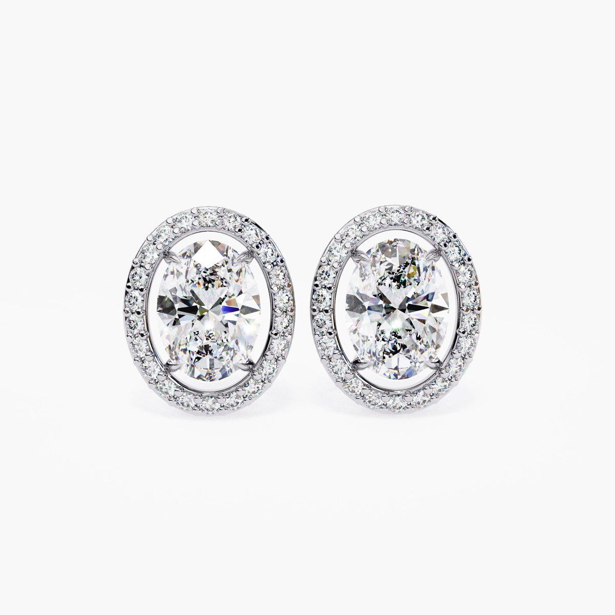 A pair of 14k white gold oval stud earrings with lab-grown center diamonds, each surrounded by a floating halo of round diamonds.