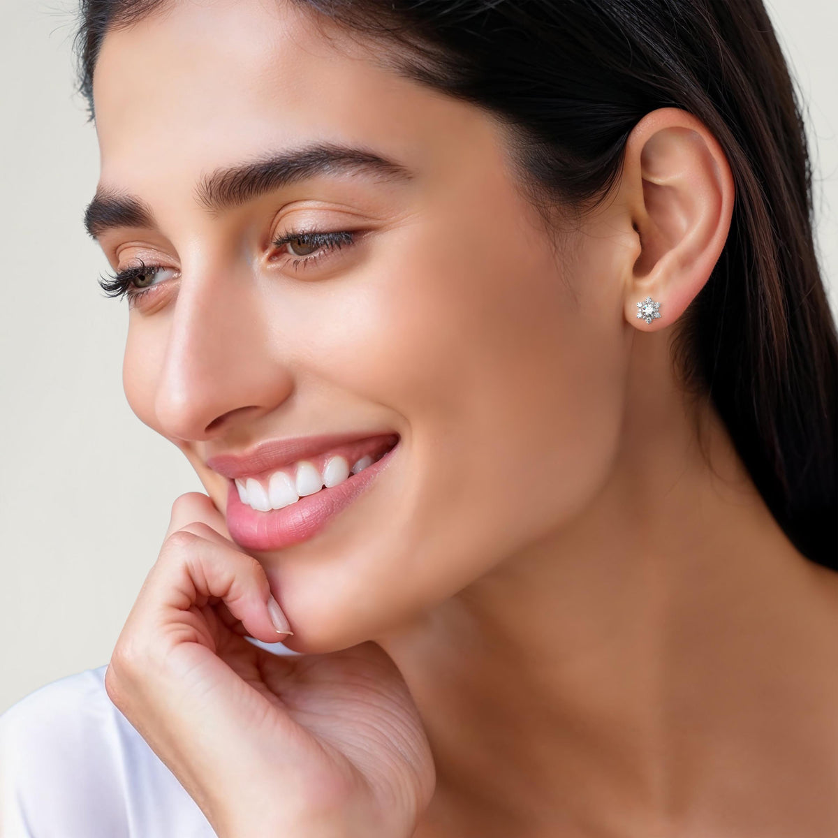 A woman wearing one of the earrings, showing how the snowflake-shaped stud sits on the earlobe.