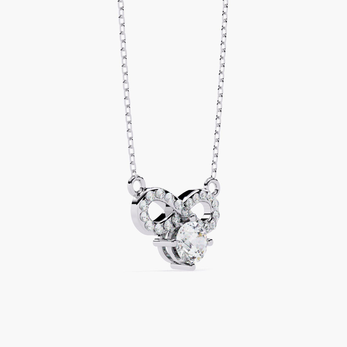 A white gold infinity necklace with a diamond solitaire stone under the infinity symbol.