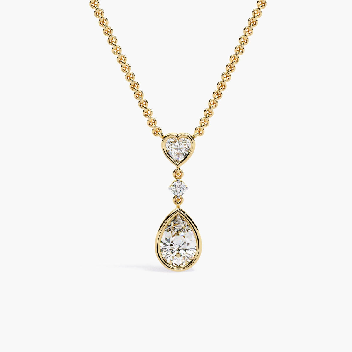 A gold chain necklace with a pear-shaped diamond pendant and a heart-shaped diamond accent.