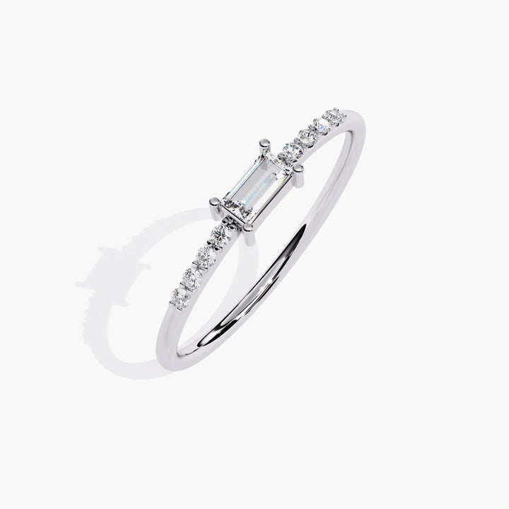 A thin white gold band with a small rectangular diamond in the center and smaller round diamonds on either side of the center stone.