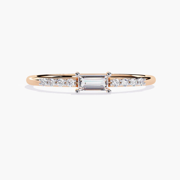 A thin rose gold band with a small rectangular diamond in the center and smaller round diamonds on either side of the center stone.