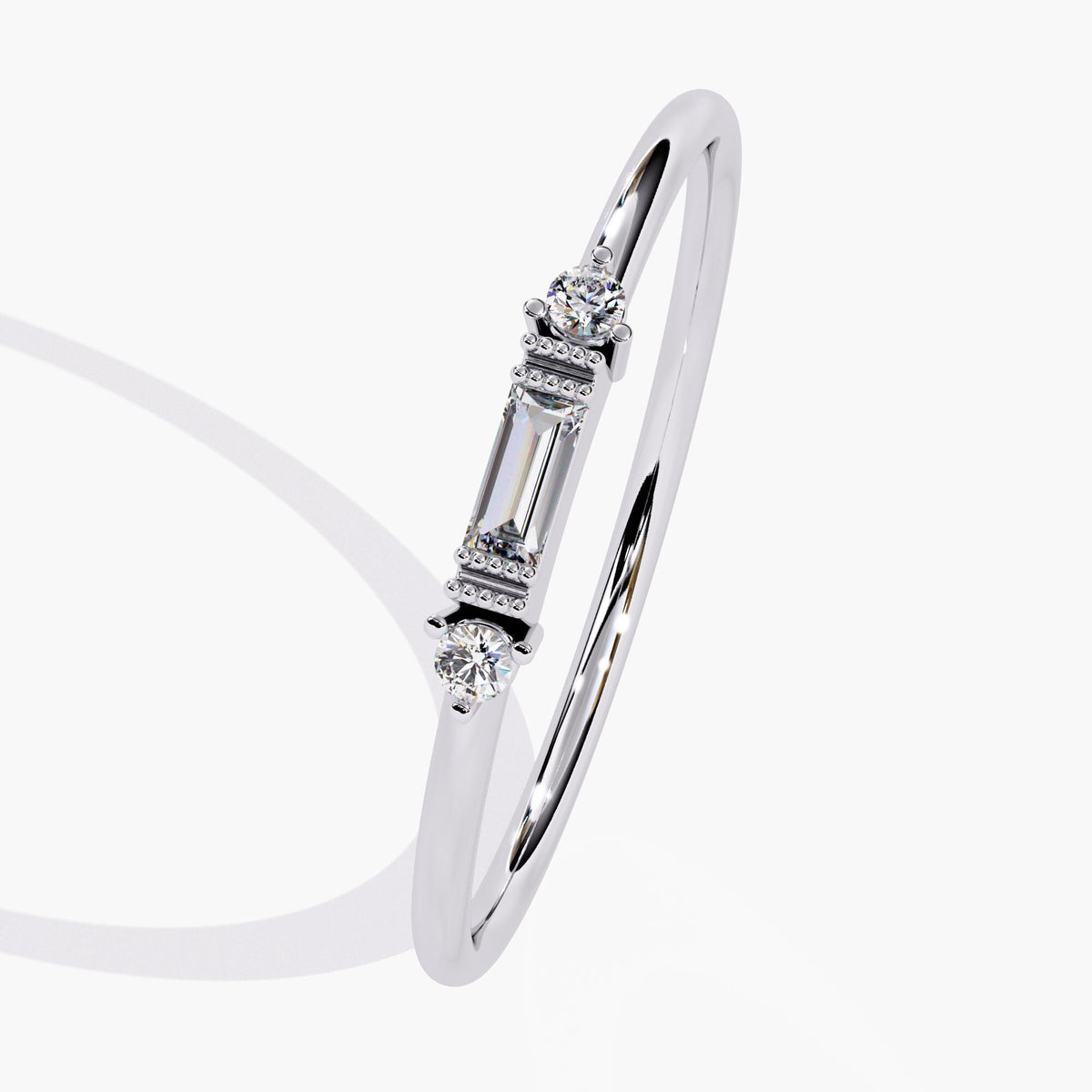Angled view of a white gold baguette diamond ring with a slim band and two round side diamonds. A delicate ring ideal for minimalist engagement or promise ring gifting.